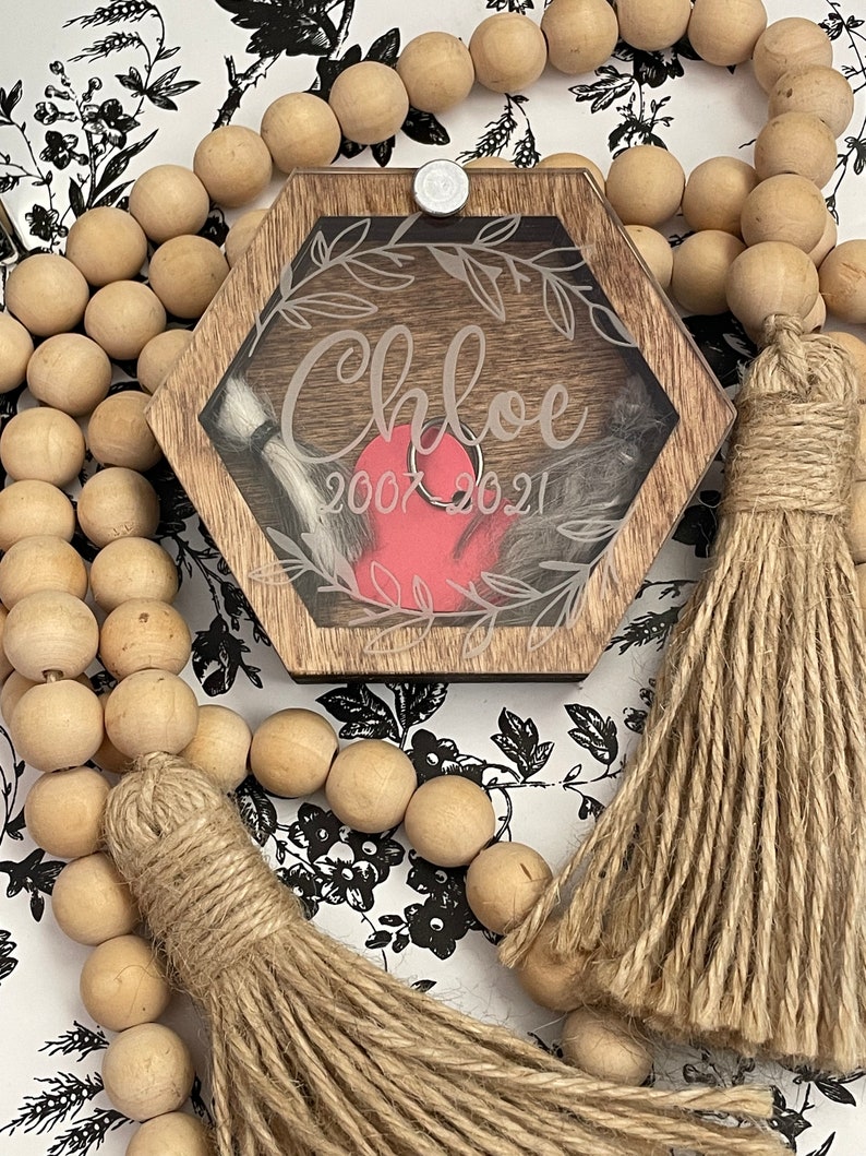 May include: A hexagonal wooden box with a clear lid and a red heart inside. The box is decorated with a floral design and the name "Chloe" and the dates "2007 2021".