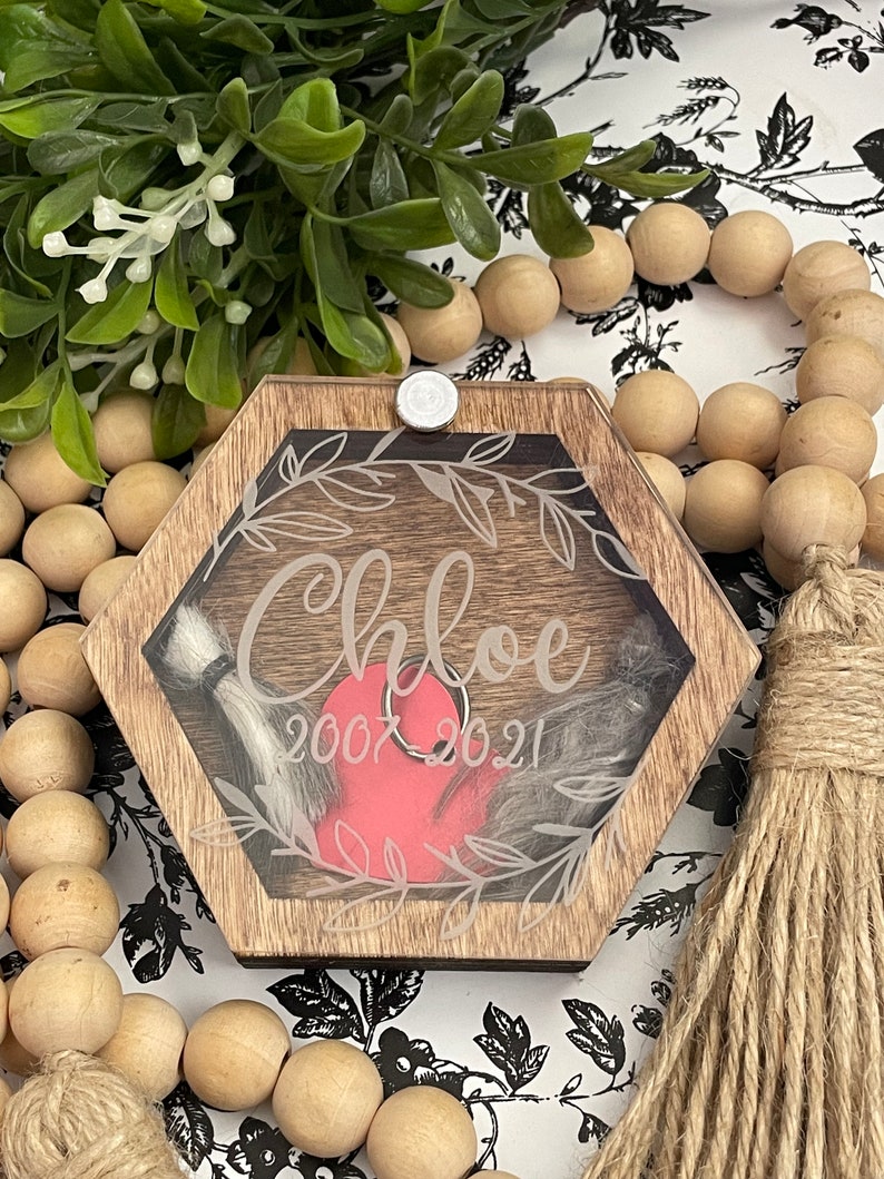 May include: A hexagonal wooden box with a clear lid, featuring a heart-shaped compartment and the inscription "Chloe 2007 2021".