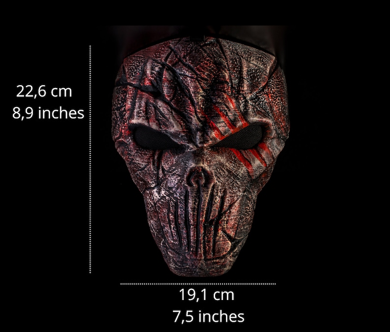 May include: A red and black skull mask with a textured surface and red paint streaks. The mask is 8.9 inches tall and 7.5 inches wide.
