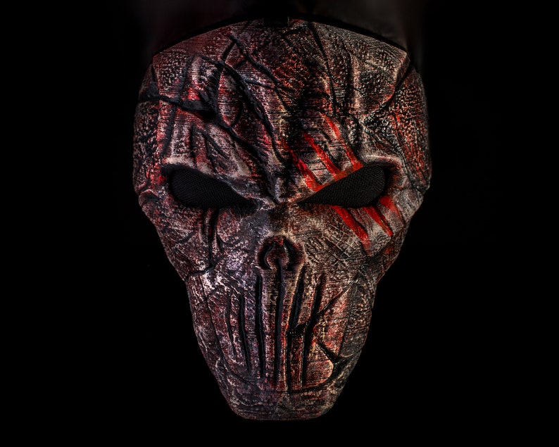 May include: A red and black Halloween mask with a skull design and red streaks across the eyes.