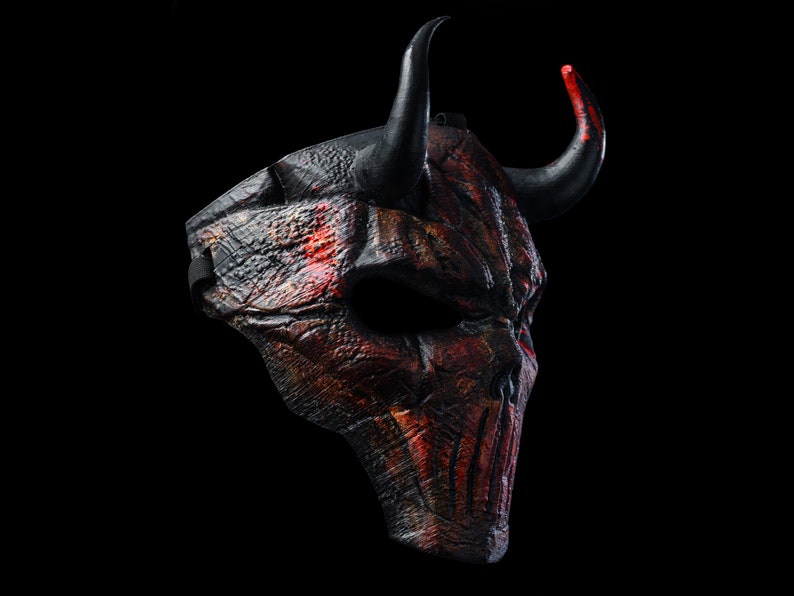 K&ouml;nnte beinhalten: Eine schwarze und rote Teufelmaske mit H&ouml;rnern. Die Maske ist aus einem strukturierten Material gefertigt und hat ein detailliertes Design.