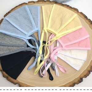 May include: A set of eight face masks in various colors, including light blue, yellow, pink, white, and gray. The masks are made of a soft, breathable fabric and have adjustable ear loops.