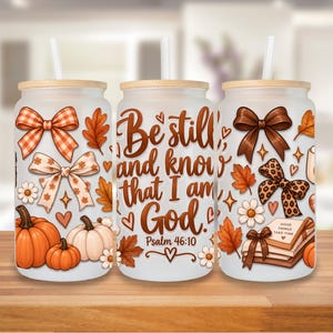 May include: Three frosted glass tumblers with bamboo lids and straws, featuring autumn-themed graphics including orange and white pumpkins, brown bows, leopard print bows, fall leaves, daisies, and the text Be still and know that I am God.