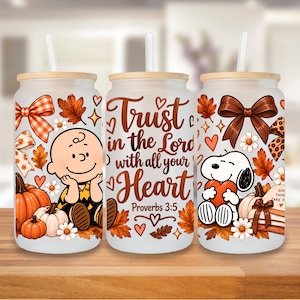 May include: Three frosted glass tumblers with bamboo lids and straws, featuring a fall-themed design with Charlie Brown, Snoopy, pumpkins, autumn leaves, bows, and the text Trust in the Lord with all your Heart Proverbs 3:5 in brown script.