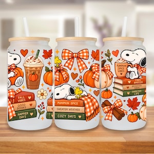 Peut inclure: Trois gobelets en verre dépoli avec couvercles en bambou et pailles, ornés d'illustrations de Snoopy et Woodstock, de citrouilles orange, de nœuds à carreaux, de feuilles d'automne, de cannelle et de livres avec le texte Fall Vibes et Pumpkin Spice.