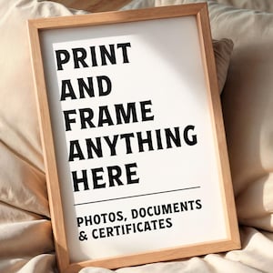 May include: A framed print with the text "PRINT AND FRAME ANYTHING HERE" in bold black letters. Below the text is a horizontal line, followed by "PHOTOS, DOCUMENTS & CERTIFICATES". The frame is made of light-coloured wood.