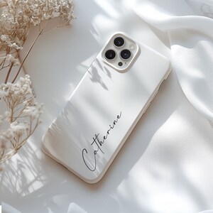 May include: White phone case with a black inscription that reads "Catherine".
