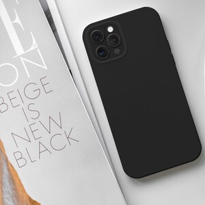 May include: A black phone case with a camera lens cutout. The case is made of a smooth, matte material.