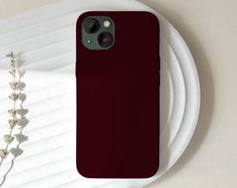 Puede incluir: Una funda de teléfono de color rojo oscuro con un recorte para el objetivo de la cámara.