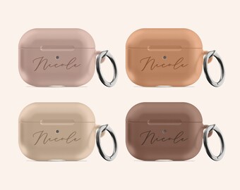 May include: Four Airpods cases in different colours: pink, orange, beige, and brown. Each case has a silver ring attached and the name "Nicole" is engraved on the front.
