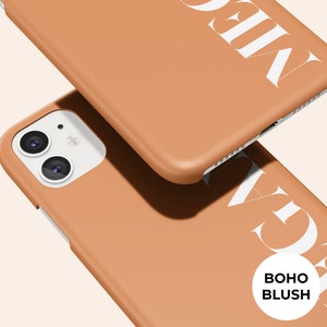 Puede incluir: Dos fundas de tel&eacute;fono de color terracota con texto blanco. Una funda es parcialmente visible, con la palabra "MEGA" impresa. La otra funda est&aacute; en primer plano, con la palabra "GAGA" impresa. Las palabras "BOHO BLUSH" est&aacute;n en un c&iacute;rculo blanco.
