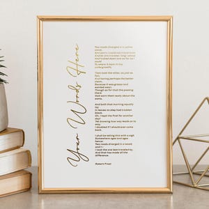 May include: A gold-framed print displaying a poem by Robert Frost. The text is black, with the words "Your Words Here" in gold script. The poem describes two roads diverging in a wood, a classic literary piece.