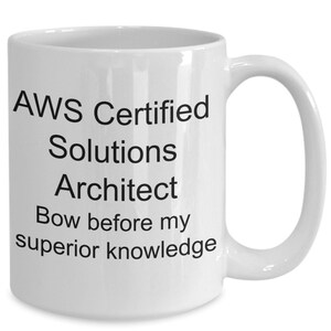May include: White ceramic coffee mug with black text that reads "AWS Certified Solutions Architect Bow before my superior knowledge".