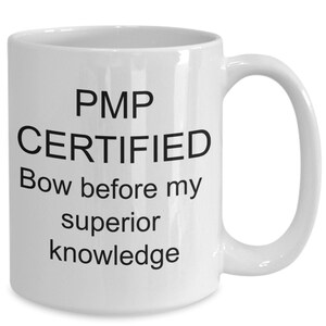May include: White ceramic coffee mug with black text that reads "PMP CERTIFIED Bow before my superior knowledge".