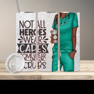 Puede incluir: Un vaso de acero inoxidable con un acabado de purpurina plateada. El vaso presenta un gráfico negro que dice "Not all heroes wear capes some wear scrubs" con un gráfico de latido del corazón. El vaso se muestra con una tapa y una pajita. El vaso también se muestra junto a un gráfico de una mujer que lleva una blusa y pantalones de color verde azulado, sosteniendo una taza de café.