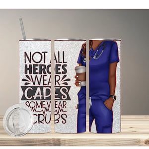 May include: A silver glitter tumbler with a black graphic that reads "Not all heroes wear capes some wear scrubs". The graphic is surrounded by a heart rate line. The tumbler is next to a cartoon illustration of a woman wearing blue scrubs and a stethoscope. She is holding a cup of coffee.