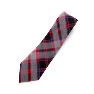 May include: A diagonally-oriented necktie with a plaid pattern. The tie features a grey base with black, red, and blue intersecting lines, creating a classic tartan design. The tie is made of a woven fabric and is set against a white background.