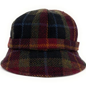 以下が含まれることがあります： 黒、バーガンディ、青、金などの色が混ざったチェック柄のクロッシュハット。帽子は、構造化されたつばとクラウンの周りのバンドが特徴です。生地は質感のある外観をしています。