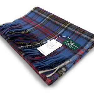 May include: A blue, red and white plaid scarf with fringe. The scarf is folded and has a tag attached that reads "Dargain Tweeds 100% Pure Wool".