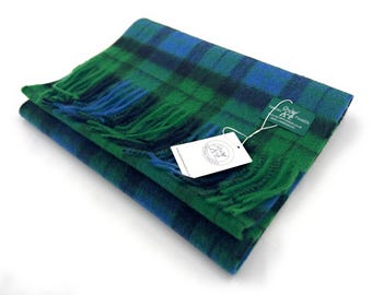 May include: A green, blue, and black plaid scarf with fringe. The scarf is folded in half and has a tag attached that reads "Tartan Tweeds, 100% Pure New Wool, Made in Scotland".