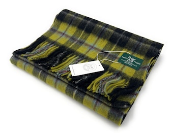May include: A yellow, black, and gray plaid scarf with fringe. The scarf is folded and has a tag attached that reads "Orkney Tweeds, Handwoven in Orkney, Pure Wool".