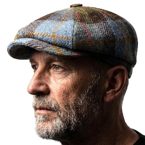 May include: A multi-colored plaid newsboy cap. The cap features a mix of blue, green, brown, and red hues. The cap has a rounded crown and a short, stiff brim. The cap is made of a textured fabric.