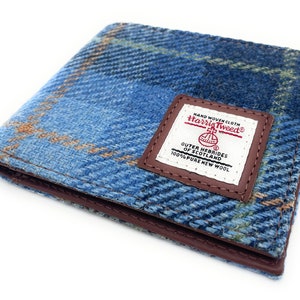 Może przedstawiać: Portfel z niebieskiego i brązowego tweedu z brązową skórzaną lamówką i etykietą z napisem "HAND WOVEN CLOTH Harris Tweed ① OUTER HEBRIDES OF SCOTLAND 100% PURE NEW WOOL".