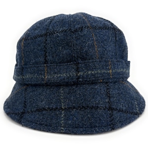 以下が含まれることがあります： 青いチェック柄のバケットハット。青色の濃淡でクラシックなチェック柄が施され、細い茶色と黒のラインが入っています。つばはしっかりとした作りで、クラウンの周りにバンドが付いています。