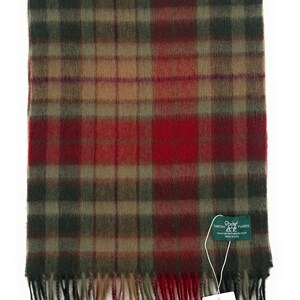 May include: A red, green, and brown plaid scarf with fringed edges. The scarf has a tag attached that reads "Tartan Tweeds, 100% Wool".