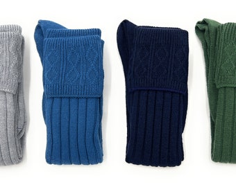 Op de afbeelding: Vier paar lange sokken in verschillende kleuren: grijs, blauw, donkerblauw en groen. De sokken hebben een geribbelde textuur en een kabelbreipatroon aan de bovenkant.