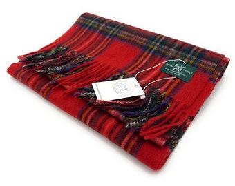 May include: Red and green plaid wool scarf with fringed edges. The scarf is folded and has a tag attached that reads "Tartan & Tweeds 100% Wool".