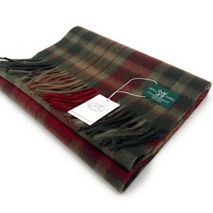 May include: A folded green, red, and brown plaid scarf with fringe. The scarf has a tag attached that reads "Harris Tweeds" and includes a website address.