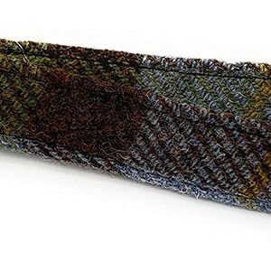 May include: A brown, blue, and green tweed strap with a white label that reads "Harris Tweed" and "Handwoven in the Outer Hebrides, Scotland".