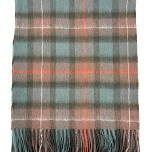 May include: A rectangular scarf with a plaid pattern in shades of gray, teal, and brown, accented with thin white and orange stripes. The scarf has a fringed edge. This accessory is suitable for cold weather.