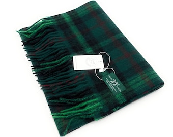 May include: A folded green and black plaid scarf with fringed edges. The scarf has a tag attached with text and a logo. The scarf is made of a soft, woven material.