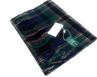 May include: A folded green, blue, and red plaid scarf with fringe. The scarf has a tag attached. The scarf is made of a soft material. The scarf is a classic accessory.
