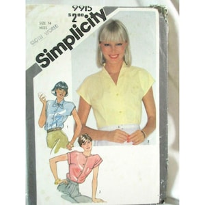 Puede incluir: Un sobre de patrón de costura Simplicity, número 9915, talla 14, con ilustraciones de tres camisas diferentes de manga corta con botones. La portada muestra una fotografía de una persona con una camisa amarilla pálida y dos dibujos de camisas en azul y rosa.