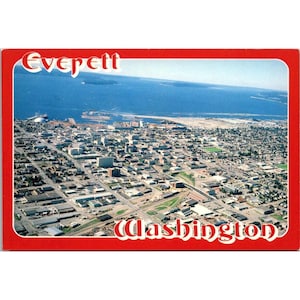 以下が含まれることがあります： エベレット、ワシントン州の航空写真が写ったヴィンテージポストカード。街は風景全体に広がっています。ポストカードは赤い縁取りで、上部に都市名、下部に州名が白い文字で印刷されています。