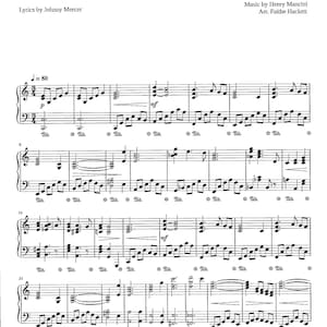 May include: Sheet music for the song "Moon River" from the film "Breakfast at Tiffany's". The music is written in standard notation with lyrics by Johnny Mercer and music by Henry Mancini. The arrangement is by Faithe Hackett.