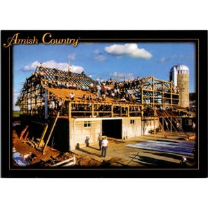 May include: A postcard featuring a large group of people working together to build a barn. The image is set against a blue sky with clouds. The text "Amish Country" is displayed in a decorative font at the top.