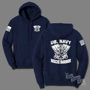 May include: Navy blue hooded sweatshirt with a white US Navy Rescue Swimmer graphic on the back. The graphic features an anchor, crossed fins, and the text "SAR". The left sleeve has a small American flag.