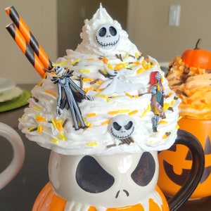 Puede incluir: Una taza tem&aacute;tica de Halloween con forma de calabaza con la cara de Jack Skellington. La taza est&aacute; cubierta con crema batida y figuritas de personajes. Incluye pajitas a rayas naranjas y negras.