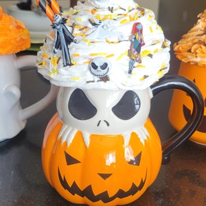 Puede incluir: Una taza de cer&aacute;mica con tem&aacute;tica de Halloween con forma de calabaza con la cara de Jack Skellington. La taza est&aacute; cubierta con crema batida y figuritas en miniatura. Incluye pajitas a rayas naranjas y negras.
