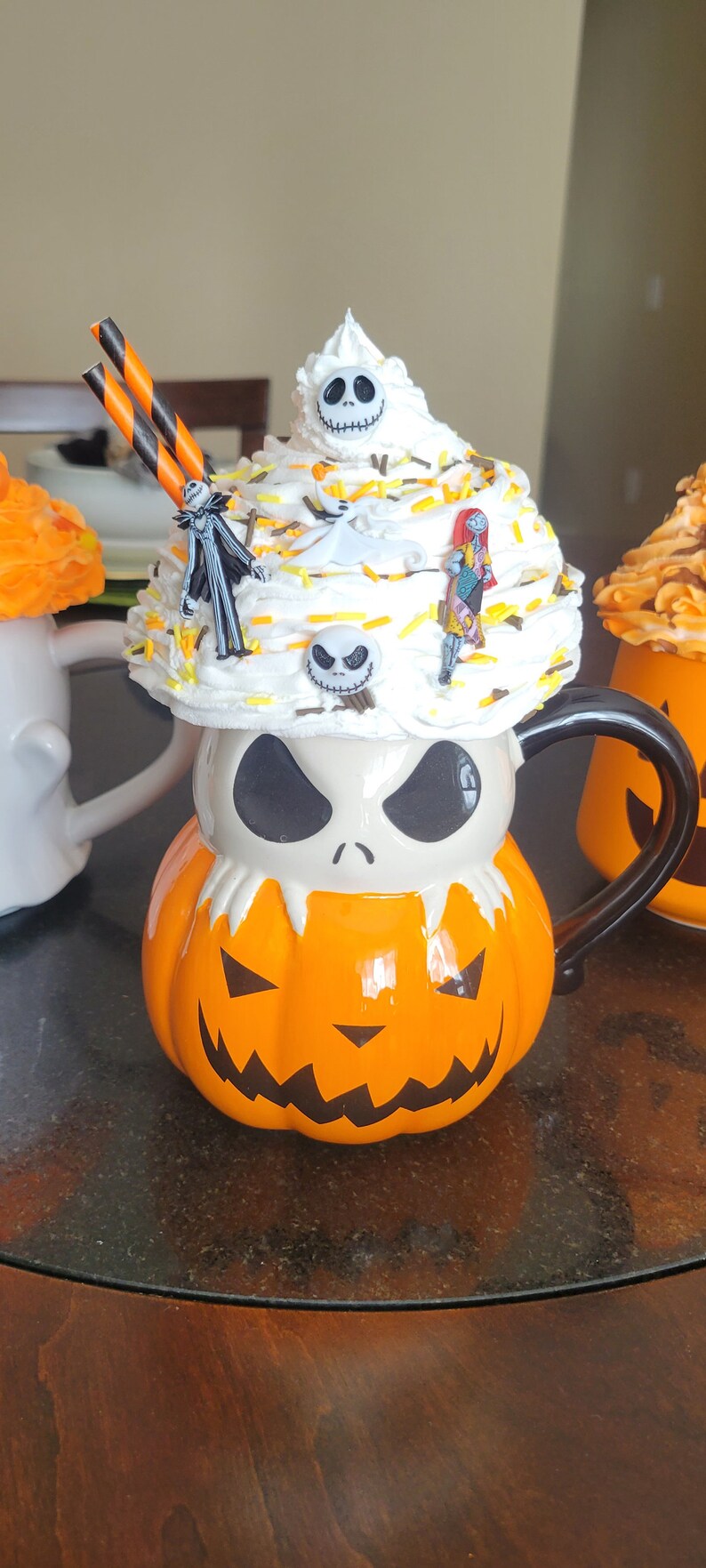 Puede incluir: Una taza de cer&aacute;mica con tem&aacute;tica de Halloween con forma de calabaza con la cara de Jack Skellington. La taza est&aacute; cubierta con crema batida y figuritas en miniatura. Incluye pajitas a rayas naranjas y negras.