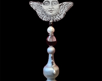 Moon face with angel wings, celestial figurine.