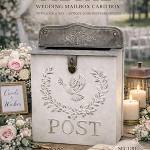May include: Vintage style metal wedding mailbox card box with lock and key. The off-white box features a dove and wreath design, with the word "POST" embossed on the front. A decorative key and cards are visible.