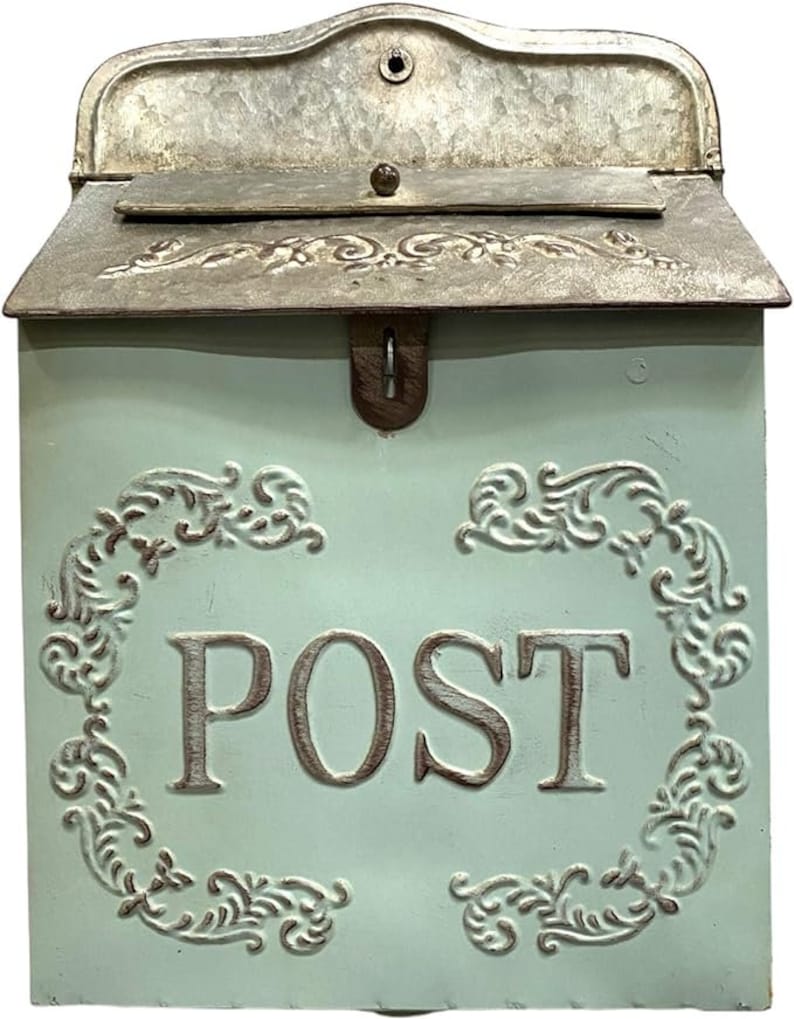 May include: A light blue metal wall-mounted mailbox featuring a hinged lid with a metallic finish and embossed floral scrollwork. The front panel displays the word POST in large capital letters, framed by decorative embossed scroll patterns.