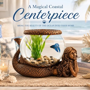 May include: A decorative mermaid-shaped aquarium with a clear glass bowl, housing a blue betta fish and green plants. The base is bronze-colored, and the text reads "A Magical Coastal Centerpiece".