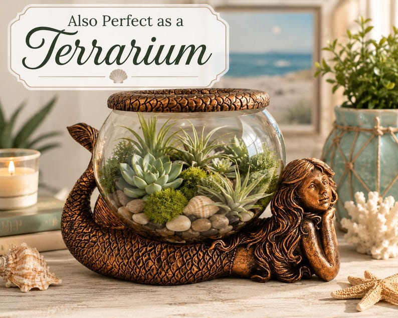 May include: A bronze-colored mermaid-shaped terrarium base supports a clear glass bowl filled with succulents, moss, and small stones. The text "Also Perfect as a Terrarium" is displayed above the terrarium. Seashells and a starfish are placed near the base.