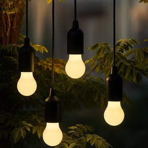 May include: Four hanging outdoor lights with black fixtures and glowing bulbs. The lights are suspended from a rope against a backdrop of green foliage. The bulbs emit a warm, inviting light, perfect for a patio or garden setting.